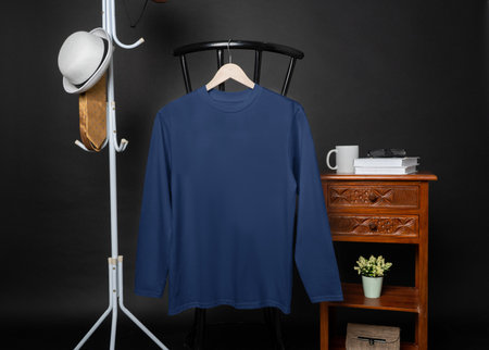 A blank Navy shirt hanged on to a chair with minimalist decorations, on a black background, shirt mockup imageの写真素材