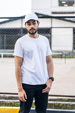 With his bearded face and stylish attire, this man strikes a pose that exudes confidence and strength, white blank cap hat and shirt mockup imageの写真素材