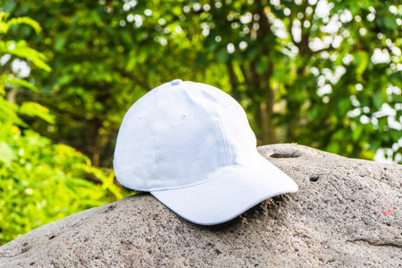 An image that captures the essence of calm and tranquility, with a white cap hat tastefully positioned above a nearby rock near the fores, white blank cap hat mockup imageの写真素材