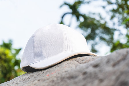 This picturesque scene is enhanced by the addition of a white cap hat, tastefully positioned above a rock near the serene forest, white blank cap hat mockup imageの写真素材