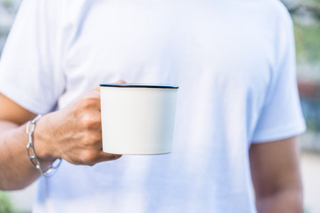 A simple yet striking photo features a hand holding up a mug, white blank mug mockup imageの写真素材