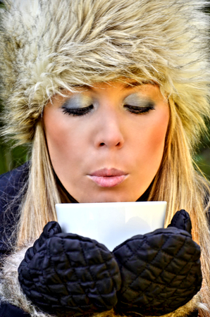 Woman blowing a cup of teaの写真素材