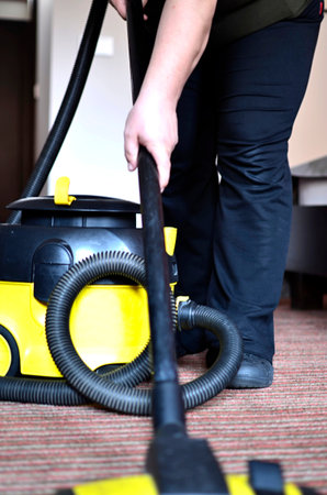 Maid cleaning the carpet with vacuum cleanerの写真素材