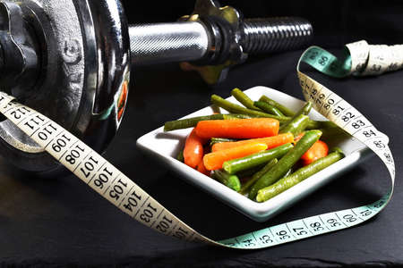 Dumbbell, baby carrot, green beans and meterの写真素材