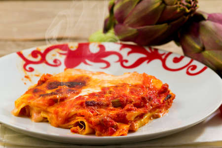 delicious hot lasagna with artichokes on a wooden backgroundの写真素材