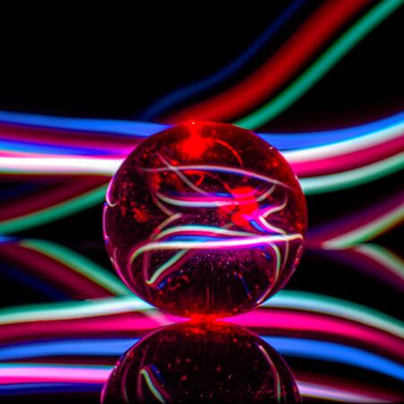 Glass ball on a black  with reflection in colored light rays, abstractの写真素材