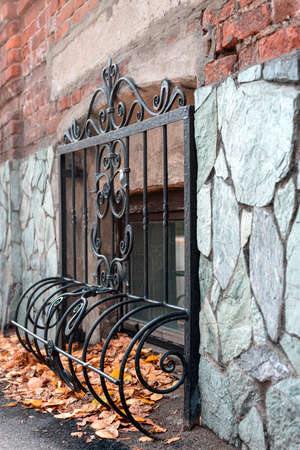 decorative metal grating on the basement window on the facade of the building, autumn leaves under itの写真素材
