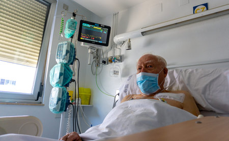 older man in a hospital bed connected to machines that monitor his vital signs