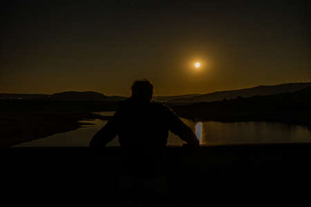 looking at the full moon on a bridgeの写真素材