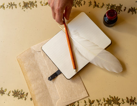 blank booklet to take notes with a white bird feather and another writing with an inkwell next to it