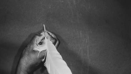 African woman's hand picks up a pen to write on a black backgroundの写真素材
