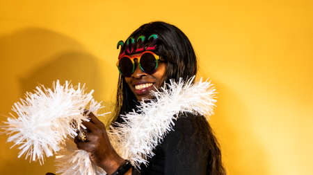 African woman with dark sunglasses in which the 2022 numbers are seen with a white boa surrounding her neckの写真素材