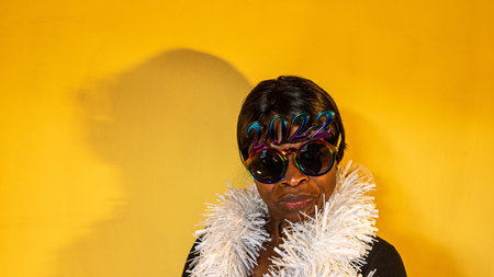African woman with dark sunglasses in which the 2022 numbers are seen with a white boa surrounding...