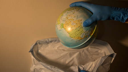 sphere of the planet earth of child study held by a hand that throws it in the trashの写真素材