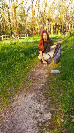 Young woman picking up trash in nature