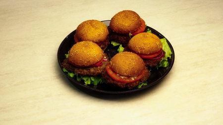 Five homemade hamburgers on black plate on uniform white backgroundの写真素材