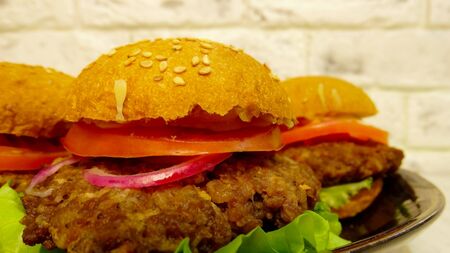 Homemade hamburgers on black plate on white brick backgroundの写真素材