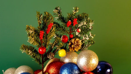 Happy New Year and Chritsmas. Silver, red and blue balls and cones in wooden basket with green christmas tree branches. Homemade christmas toys and decorations on green blured background.の写真素材
