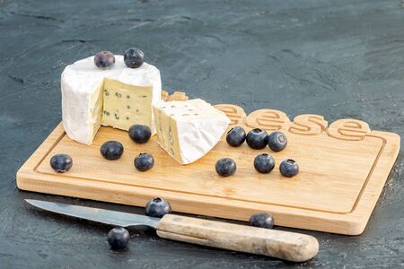 White fresh cheese brie with some blackberries on the wooden cheese board.の写真素材