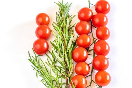 Fresh red little tomatoes cherry with a branch of rosemay on the white background.の写真素材