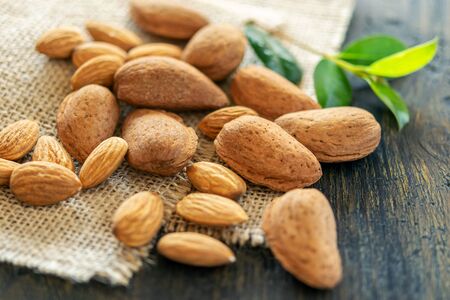 Group of peeled and unpeeled almonds on the wooden natural background. Vitamins, energy, health concept.の写真素材