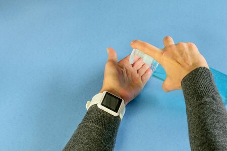 Female hands holding a bottle of liquid gel sanitizer. Wrist watch with a space for words or text. Stay home, keep your care. の写真素材