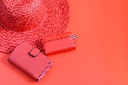Lady red straw hat, wallet and coin purse on the red background. Monochrome photo, copy space, flat lay.の写真素材