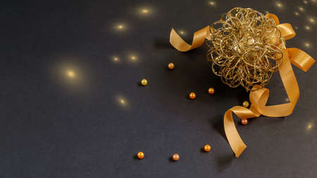 Christmas and New Year bauble with ribbon and beads on the black background. Nice golden bokeh, space for your text. Nice greeting card design.の写真素材