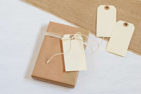 Handmade alternative gift wrapped in recycled craft paper with blank cards. Textured grunge burlap cloth background. Zero waste, plastic free gift box, mock up photo.の写真素材