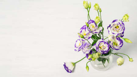 Lisianthus blu and white flowers bouquet in glass vase. Greeting card design for Mother's day, Women's day or Valentine's day. Top view, banner photo with space for your greeting text.の写真素材