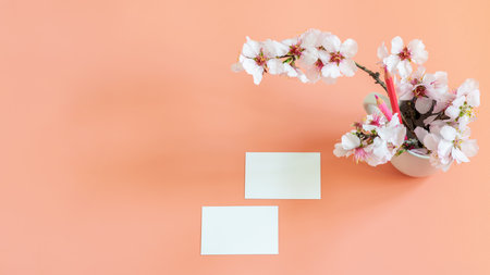 Branding business card mockup template on the pink tender background. Small almond flowers bouquet and pink pensils. Card blank for displaying your brand, website address and more purposes. Top view, banner photo.の写真素材