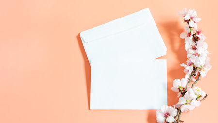 White envelope blank and branch of blooming almond on the pink background.Almond blossoms. Spring mock up template with copy space.の写真素材