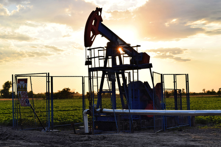 Silhouette of a grasshopper crude oil pump during sunset timeの写真素材