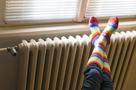 A woman in striped socks enjoying winter in a cozy, warm room (low light)の写真素材