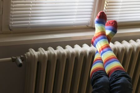 A woman in striped socks enjoying winter in a cozy, warm room (low light)の写真素材