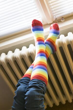 A woman in striped socks enjoying winter in a cozy, warm room (low light)の写真素材