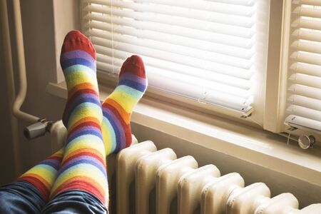 A woman in striped socks enjoying winter in a cozy, warm room (low light)の写真素材
