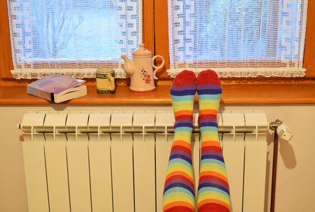A woman in striped socks enjoying winter in a cozy, warm roomの写真素材