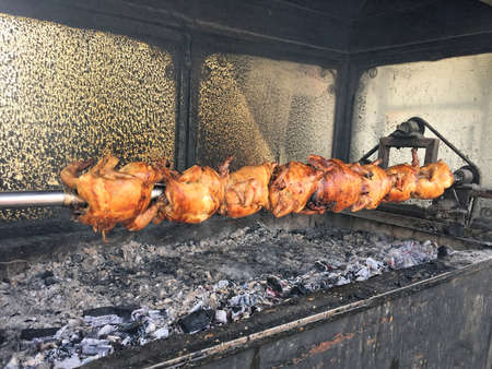 Crispy fried whole chickens on a skewer in an eatery kitchen - rotisserieの写真素材