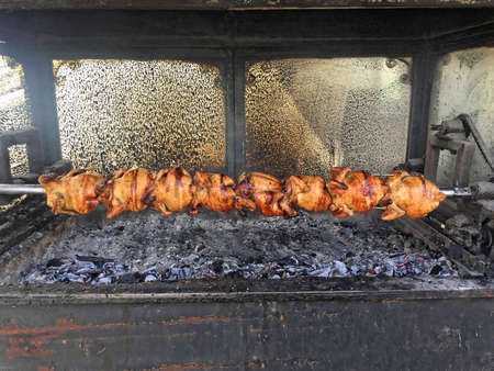 Crispy fried whole chickens on a skewer in an eatery kitchen - rotisserieの写真素材
