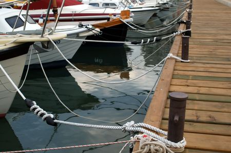 Boats tied on wooden dock in harborの写真素材