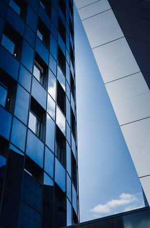 Parts of modern architecture composed into abstract triangle with a clear blue sky in the middle. The buildings are made of metal and glass with the reflection of bright blue sky with white cloud.の写真素材
