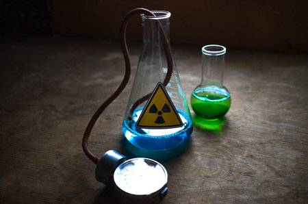 Laboratory flasks with radioactive substance of green and blue color. Production of pesticides at...