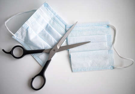 The end of the pandemic. The scissors cut the mask into two halves. The end of restrictions. You dont have to wear masks.の写真素材