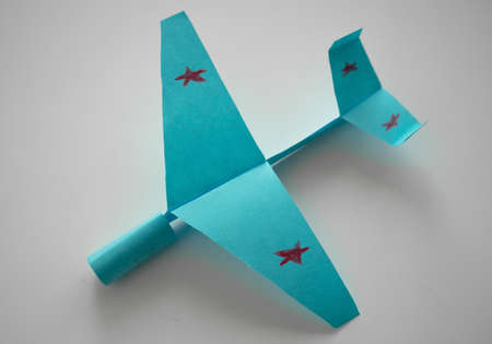 A blue paper airplane on a white isolate. A childrens airplane made of paper with red stars on the wings.の写真素材