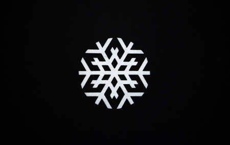 A large round snowflake of white color on a black background. Snowflake made of felt fabric on a soft textile background.の写真素材