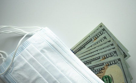White medical masks and American dollars on a light background. Purchase of medical equipment....
