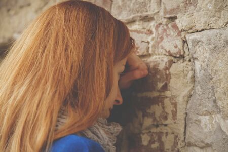 Portrait of beautiful sad woman leaning on the wall as symbol of hopelessness, depression and frustration.の写真素材