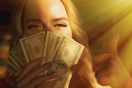 Beautiful woman with US Dollar bills making Ok gesture as if she want to say: Money really can buy You happiness.の写真素材