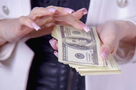 Money in hand as a symbol of success and wealth. Young successful Business Woman holding US Dollar billsの写真素材